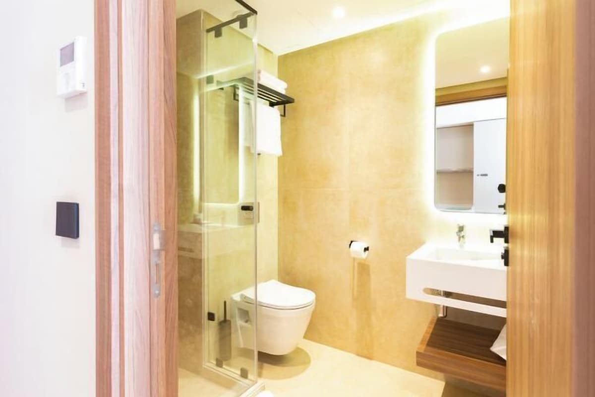 Une salle de bain moderne avec une douche à parois de verre, des toilettes blanches et un lavabo blanc avec un miroir au-dessus.