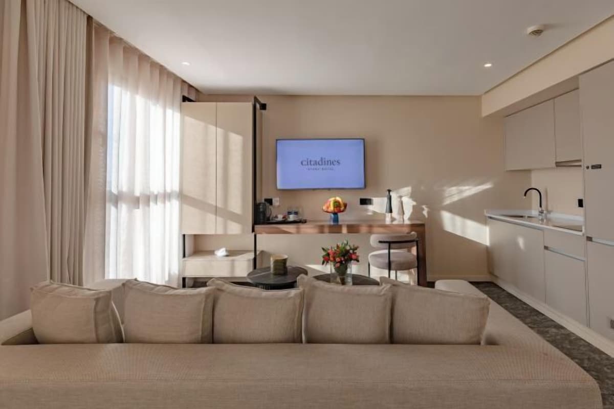 Une chambre d’hôtel moderne équipée d’un canapé, d’un téléviseur à écran plat, d’un coin cuisine et d’une table à manger.