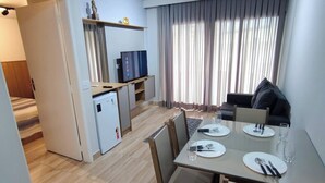 A compact living space with a dining area, kitchenette, and a small TV. - APARTAMENTO FABULOSO LIBERDADE SP (São Paulo)