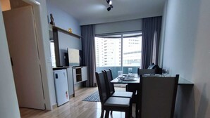 A modern living room with a dining area, a TV, and a small kitchenette. - APARTAMENTO FABULOSO LIBERDADE SP (São Paulo)