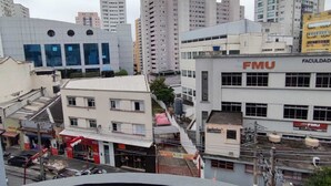 A cityscape with various buildings, including a prominent FMU building with a sign indicating it is a faculty building. - APARTAMENTO FABULOSO LIBERDADE SP (São Paulo)