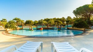 Uma área de piscina com espreguiçadeiras, um toboágua e palmeiras.