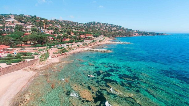 Uma cidade costeira com águas azul-claras, margem rochosa e edifícios residenciais.