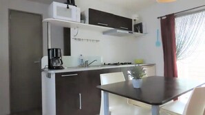 Uma cozinha compacta com área de refeições, incluindo cafeteira, pia e fogão.