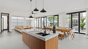 A modern kitchen with a central island, wooden cabinetry, and pendant lighting. - Kros Villa by Kozystay - Legian (Kuta)