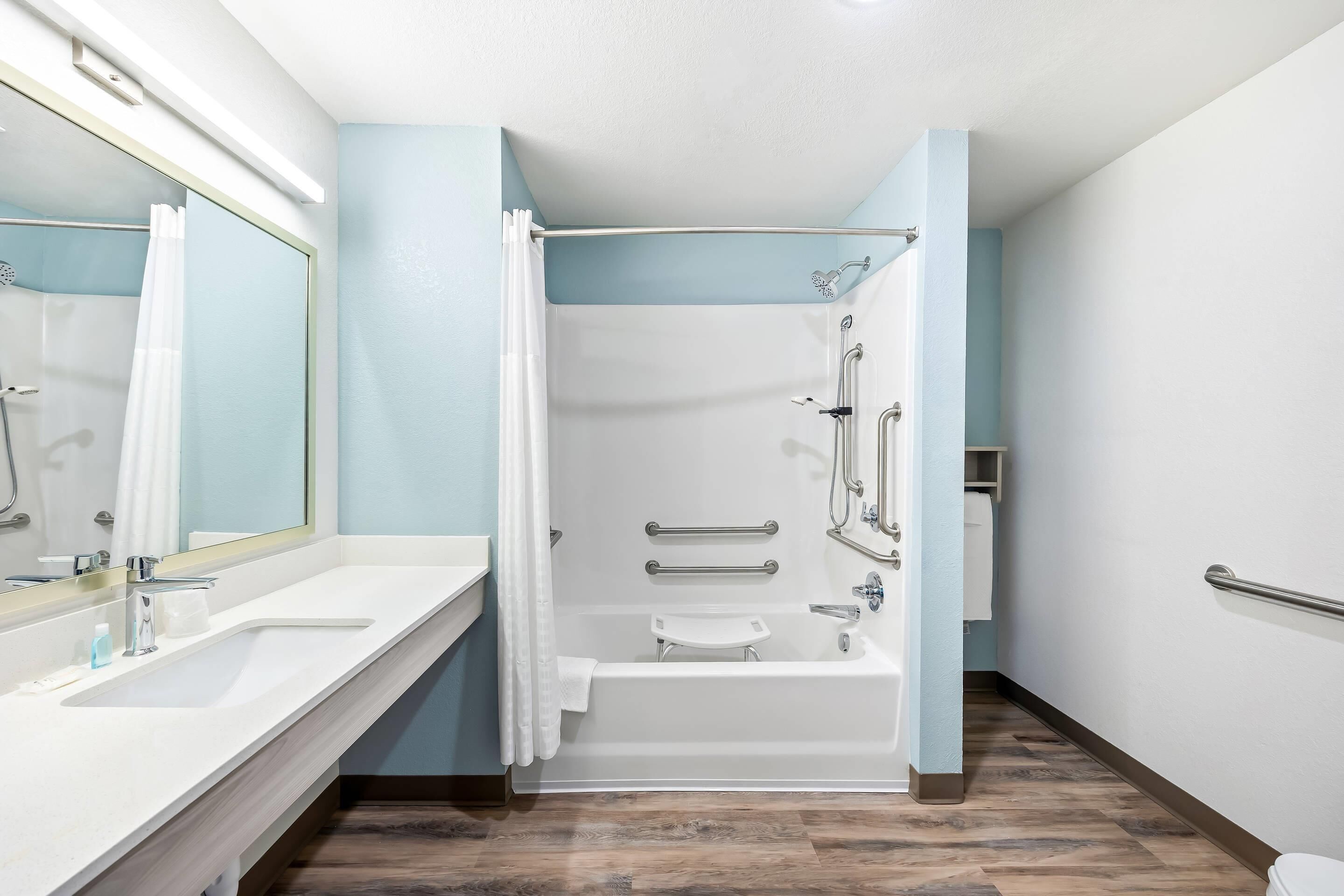 Un baño moderno con ducha, bañera y tocador con espejo.