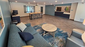Un espacio de sala moderno con un sofá, una mesa de centro y una mesa de comedor con sillas.