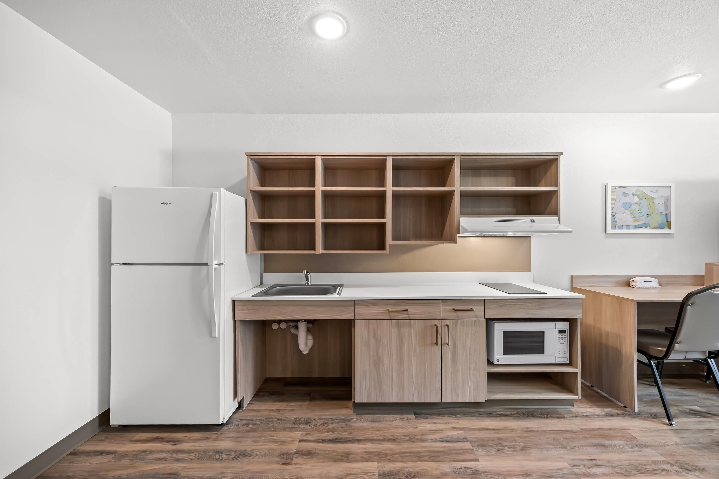 Una cocina moderna con refrigerador, microondas y armarios de madera.