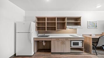 Una cocina moderna con refrigerador, microondas y armarios de madera.