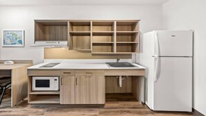 Una cocina compacta con microondas, lavamanos y refrigerador.