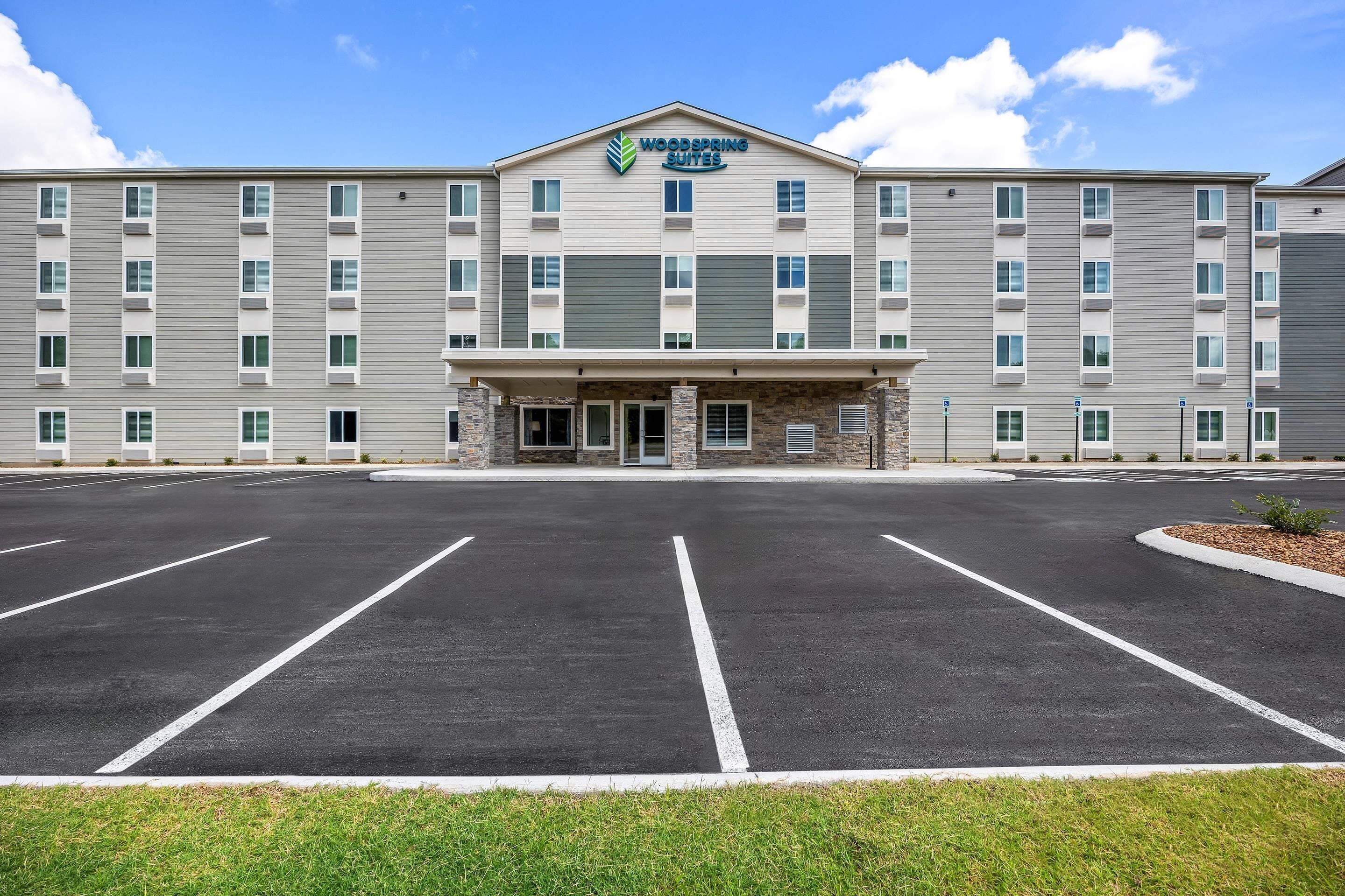 Un hôtel à plusieurs étages avec un parking situé devant.