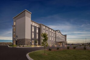A modern hotel with a multi-story structure, a covered entrance, and a well-maintained lawn. - WoodSpring Suites Jackson Hub City (Jackson)