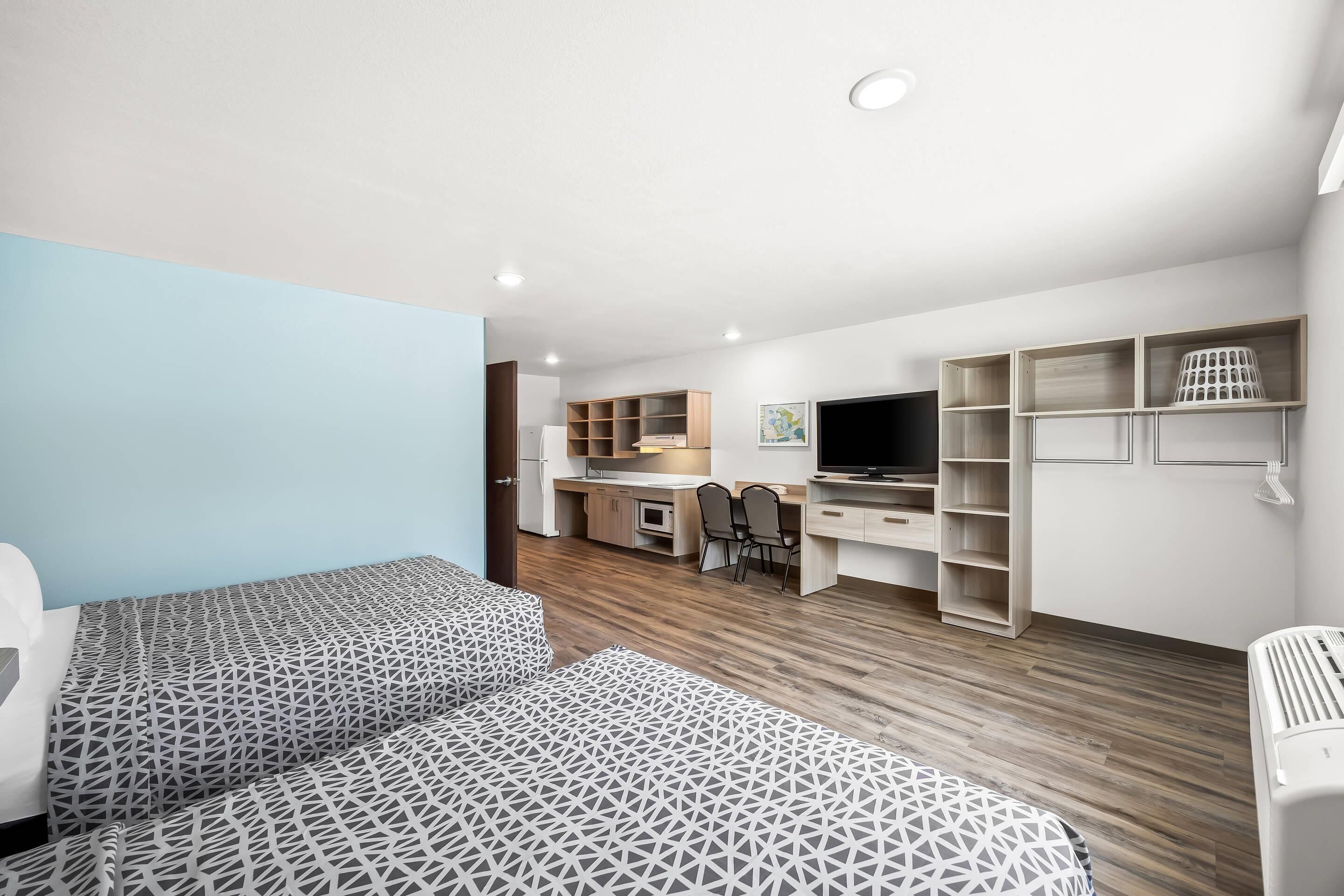 A modern, well-lit room with a bed, a desk, and a TV.