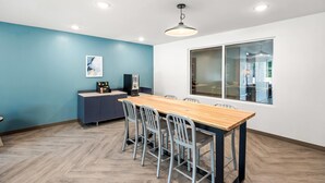 Un comedor moderno con una mesa de madera y sillas de metal, una pared azul como detalle y un ventanal grande.