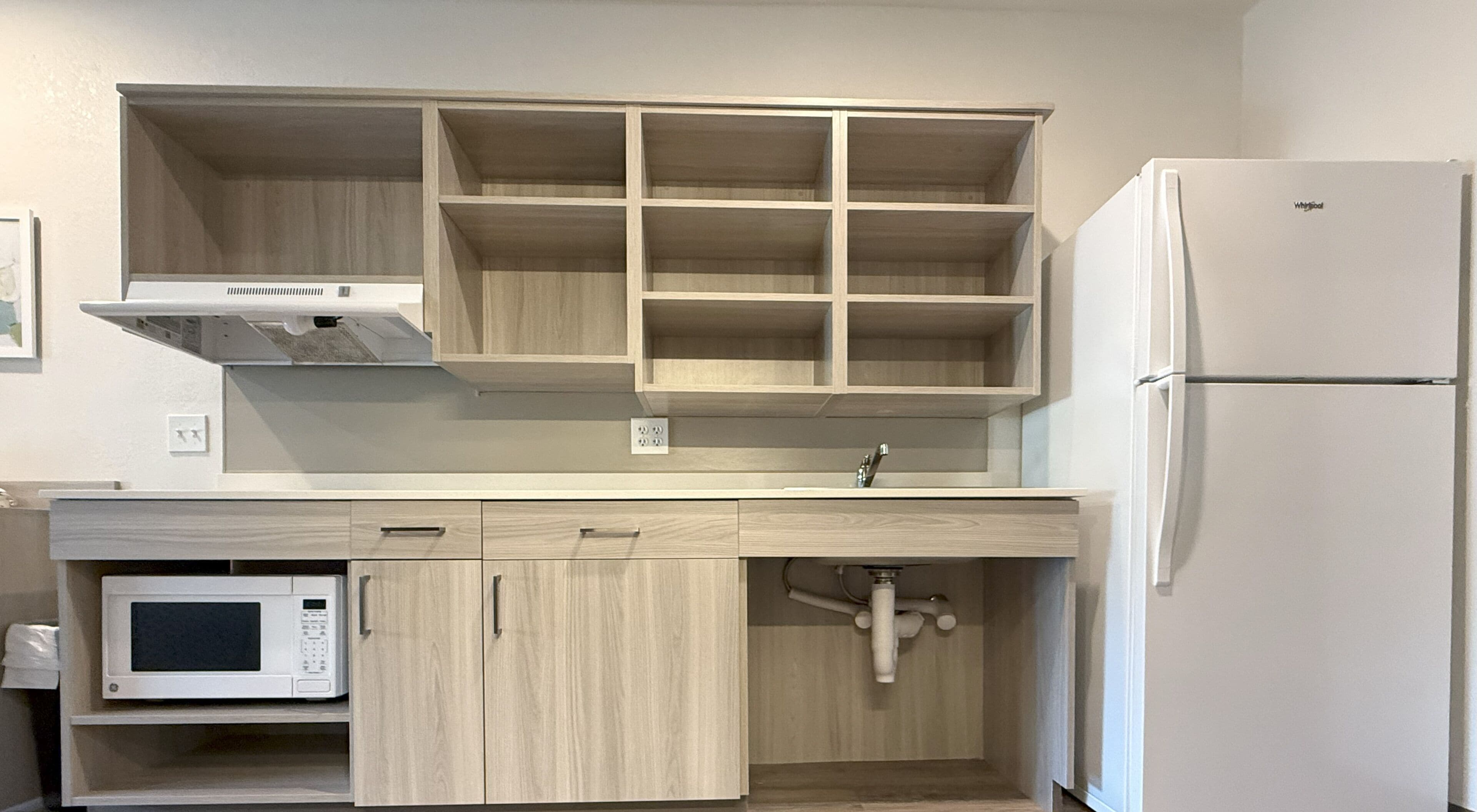 Una cocina equipada con microondas, pileta y refrigerador.