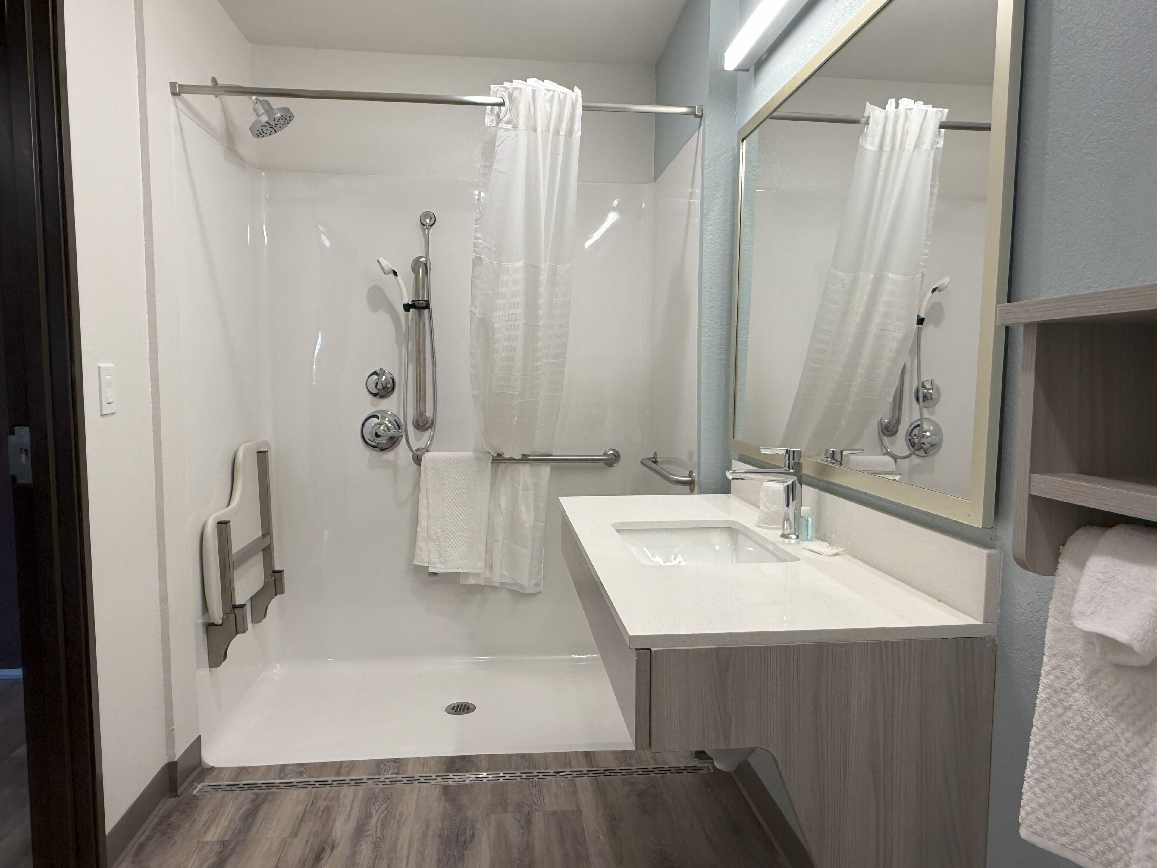 A modern bathroom with a walk-in shower, a vanity with a sink, and a mirror.