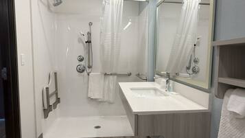 A modern bathroom with a walk-in shower, a vanity with a sink, and a mirror.