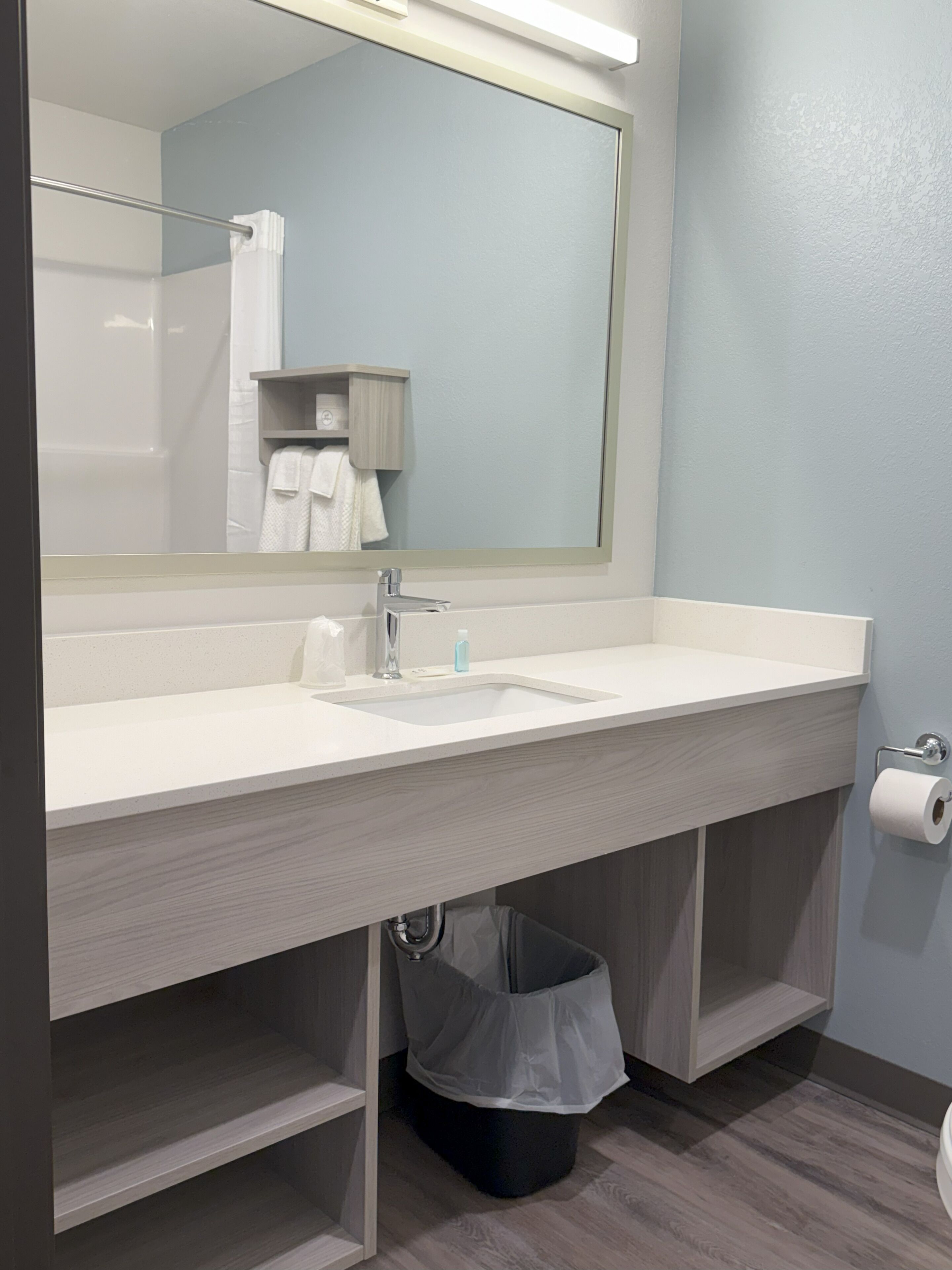 Un bany modern amb un mirall gran, un lavabo blanc i un vàter.