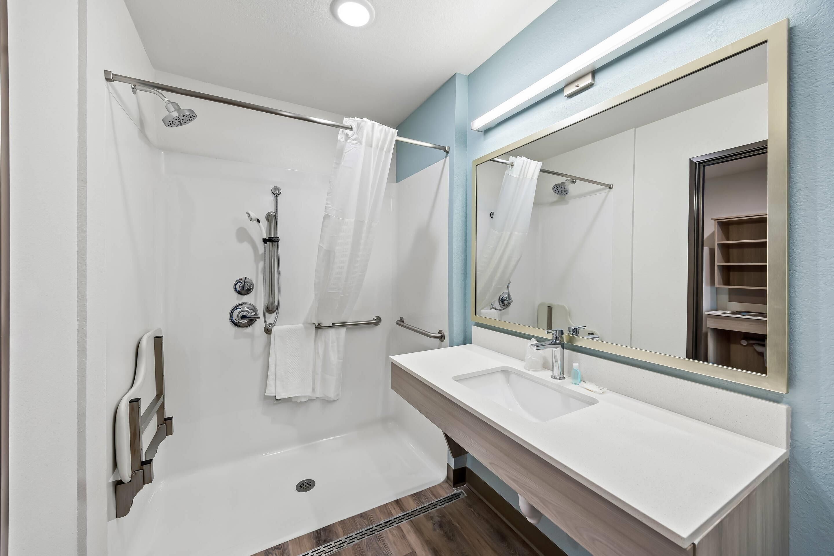 A modern bathroom with a shower, a sink, and a large mirror.
