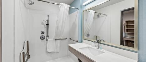 A modern bathroom with a shower, a sink, and a large mirror.