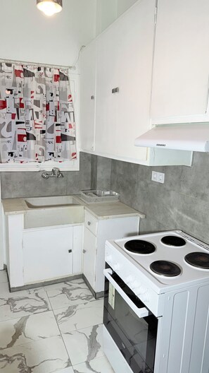 A kitchen with a white stove, a sink, and cabinets.