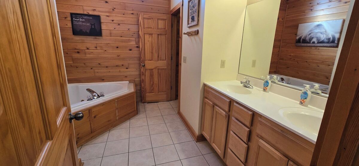 Un baño con paneles de madera, una bañera, un lavabo con espejo y un inodoro.