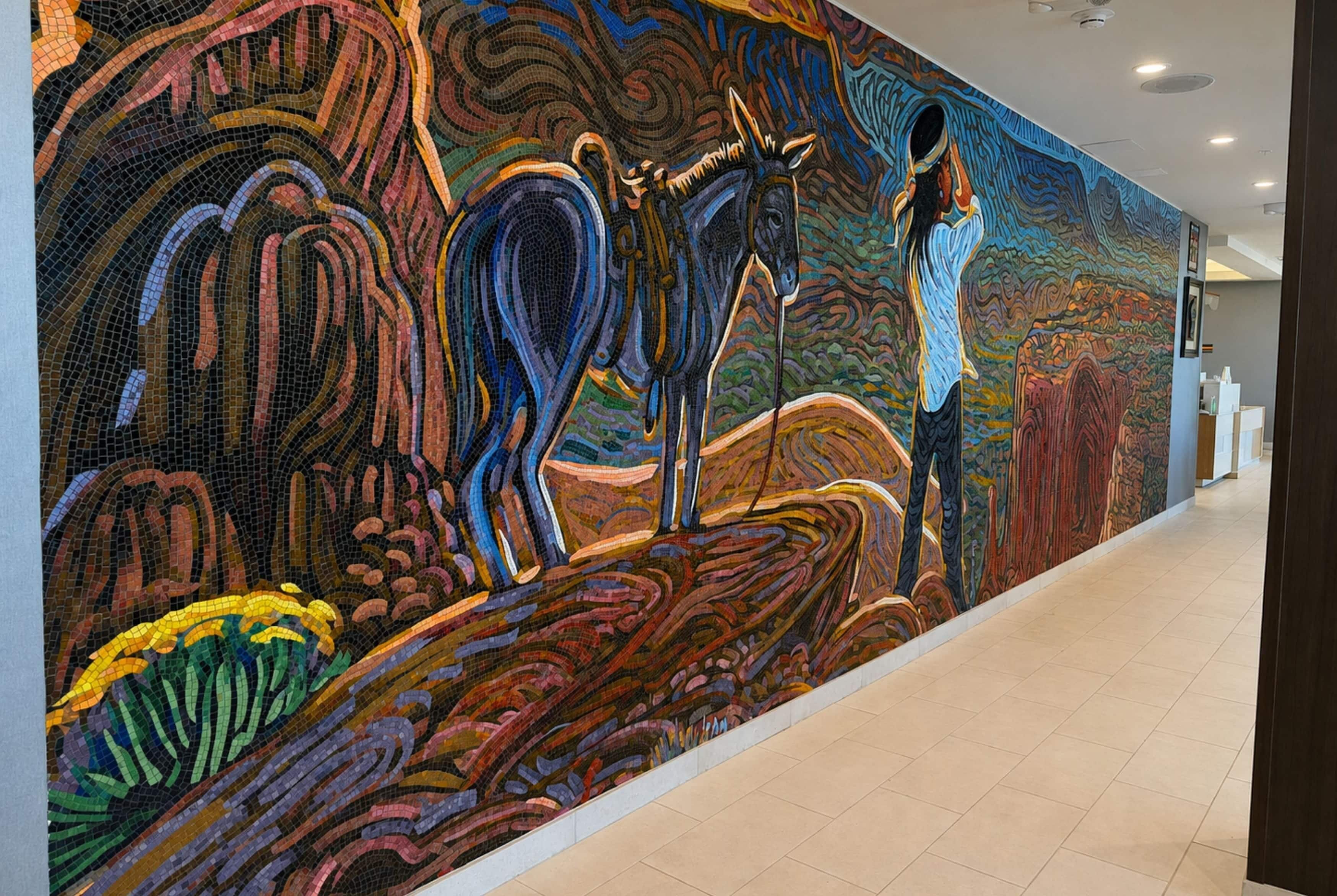 A hallway with a large, colorful mosaic mural on the wall.