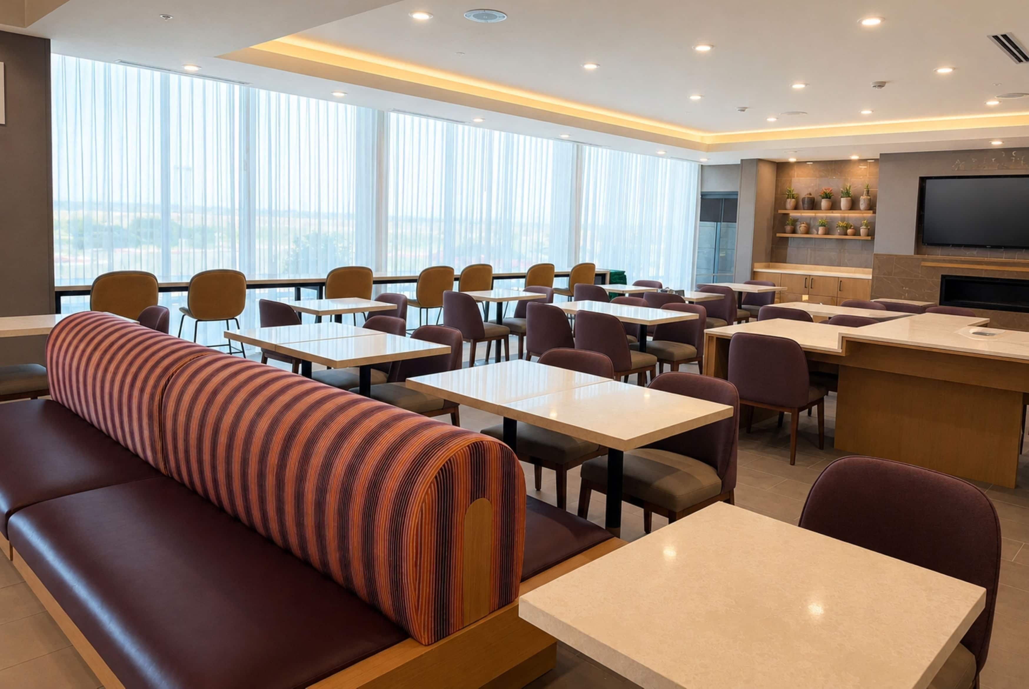 A modern dining area with tables, chairs, and a sofa.