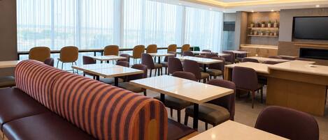A modern dining area with tables, chairs, and a sofa.