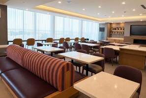 Un comedor moderno con mesas, sillas y un sofá.
