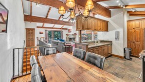 A spacious kitchen with wooden cabinets, a dining area with a large wooden table and chairs, and a staircase leading to an upper level. - 3-Level Incline Village Retreat with Fireplace (Incline Village)