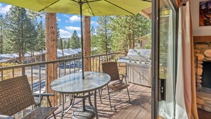 A deck with a glass table and chairs, a grill, and a view of trees and buildings. - 3-Level Incline Village Retreat with Fireplace (Incline Village)