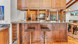 A kitchen with wooden cabinets, a granite countertop, and a central island with bar stools. - 3-Level Incline Village Retreat with Fireplace (Incline Village)