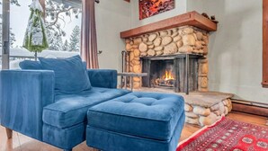 A cozy living room with a blue sofa, a stone fireplace, and a red rug. - 3-Level Incline Village Retreat with Fireplace (Incline Village)