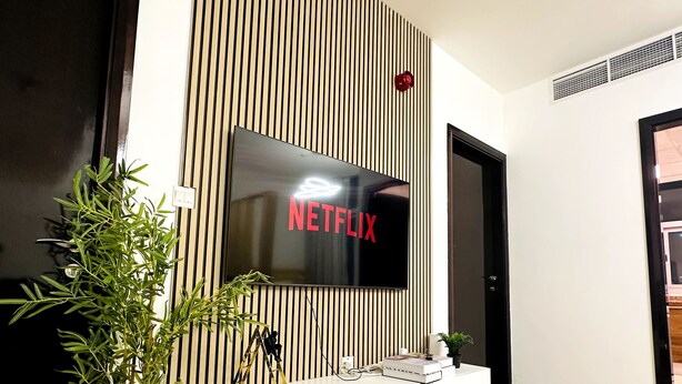 A modern living room with a large flat-screen TV mounted on a wall with vertical wooden slats.
