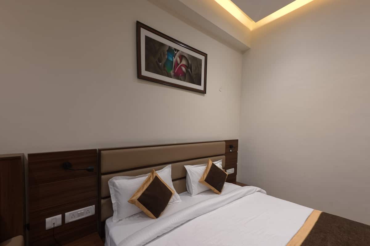 A hotel room with a bed, a nightstand, a phone, and a painting on the wall.