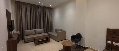 A modern living room with a sofa, a coffee table, a chair, and a TV on a wooden stand.