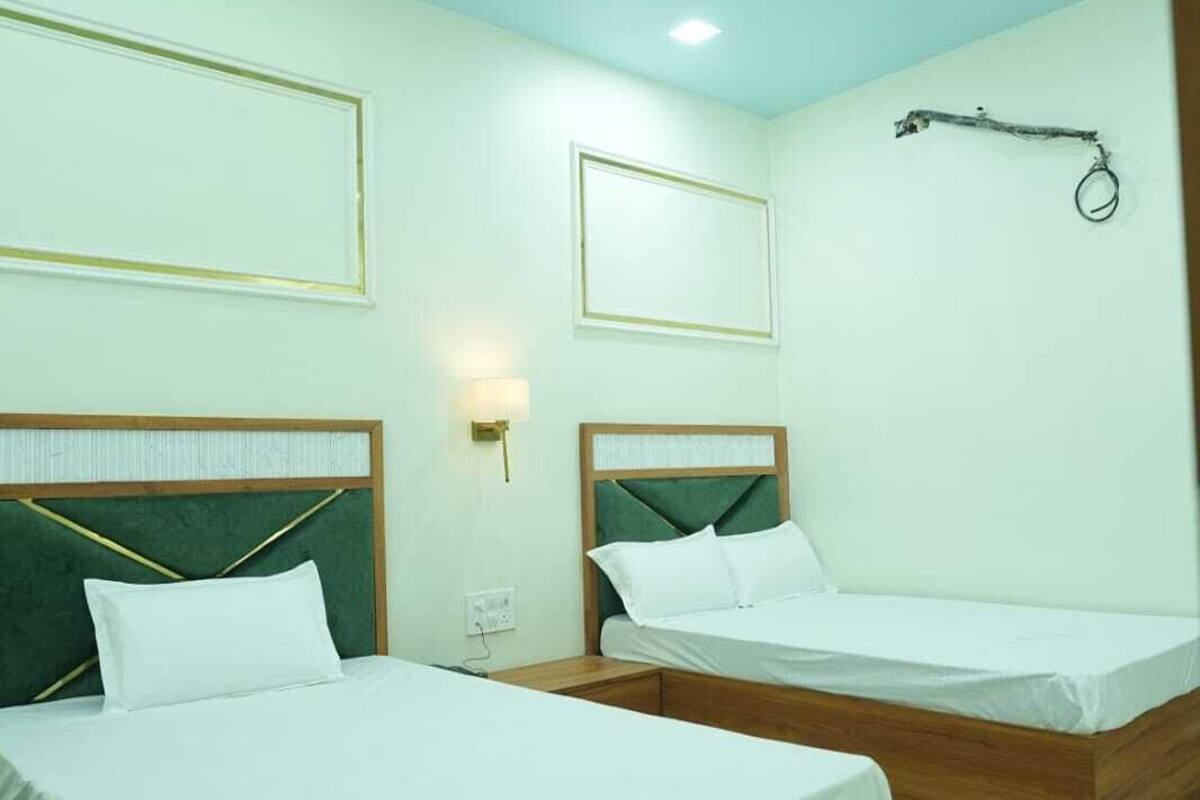 A hotel room with two wooden beds, a ceiling fan, and a wall-mounted light fixture.