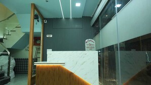 A reception desk with a marble top and wooden accents, a sign indicating 'Checkout Toam', and a reception area for 'Deep Palace Inn'. - Deep Palace Inn (Mathura)