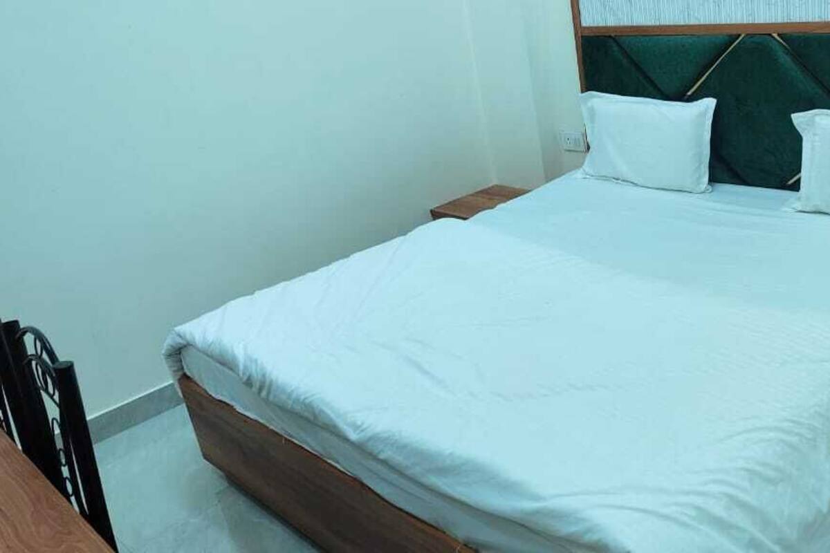 A neatly made bed with white bedding, a wooden headboard, and two bedside tables with lamps.