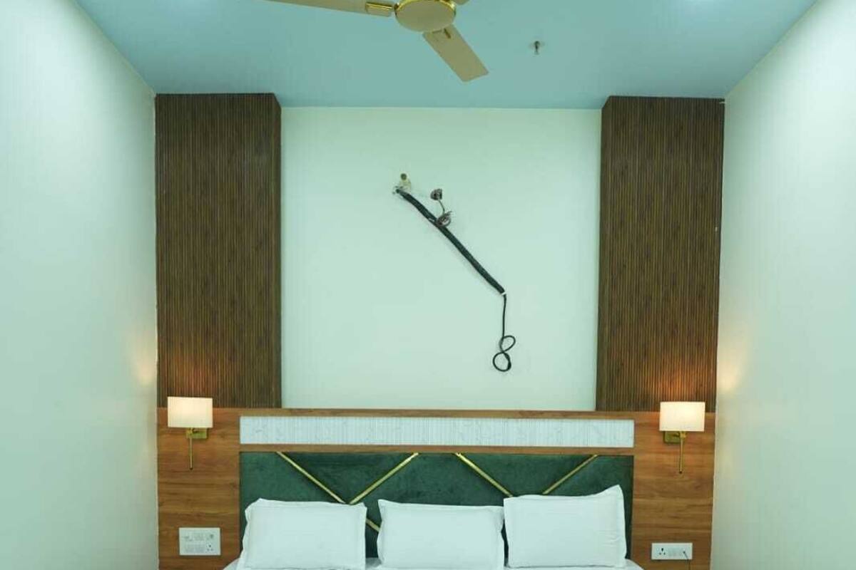 A bedroom with a bed, a ceiling fan, recessed lighting, and a wall-mounted sculpture.