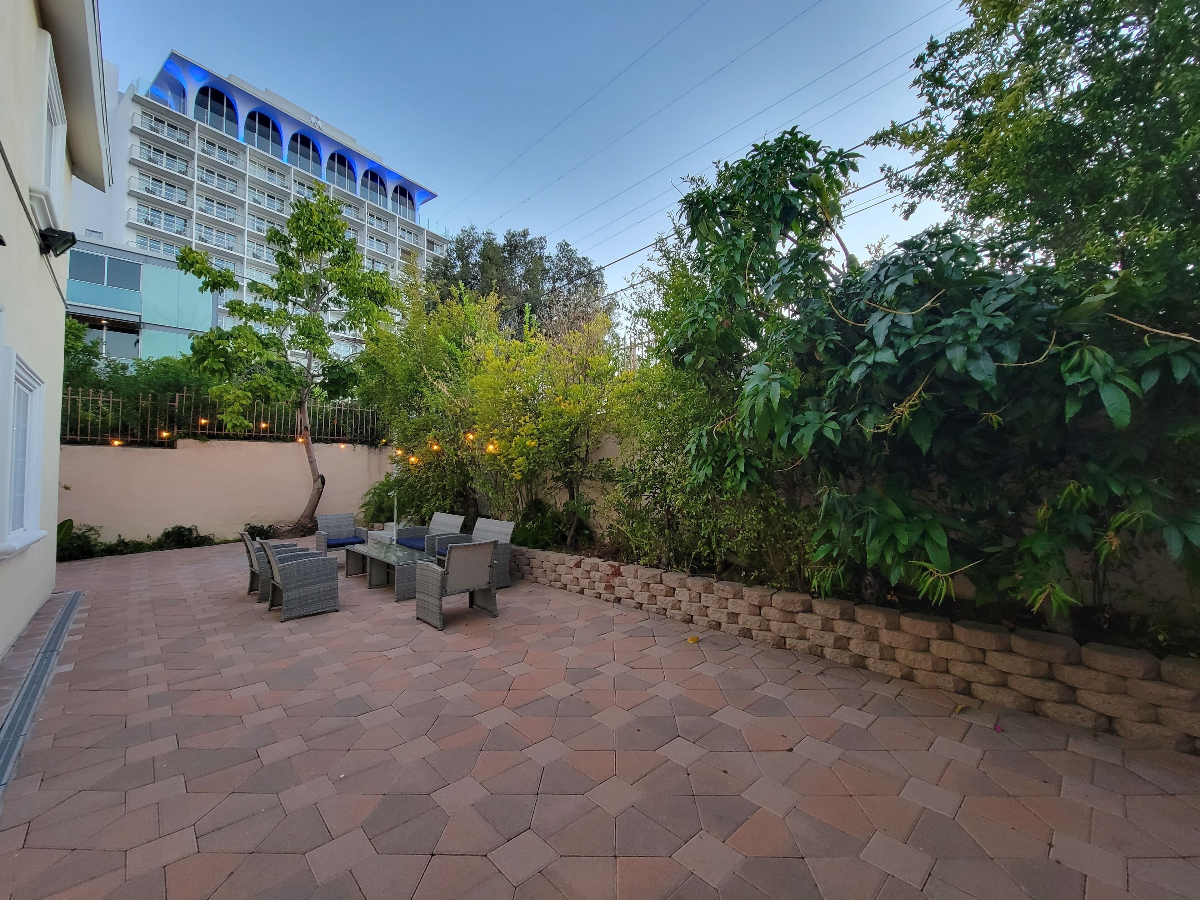 A patio with hexagonal tiles, outdoor furniture, and a brick wall.