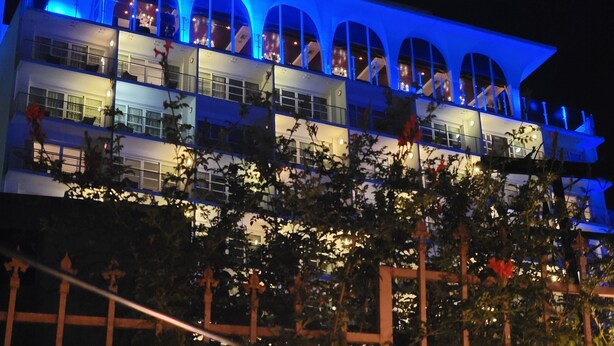 Un hotel de varios pisos con un diseño de balcón arqueado distintivo e iluminación azul.