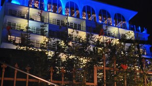 A multi-story hotel with a distinctive arched balcony design and blue lighting.