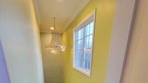 Una escalera de madera con barandilla, un candelabro y una ventana con vistas.