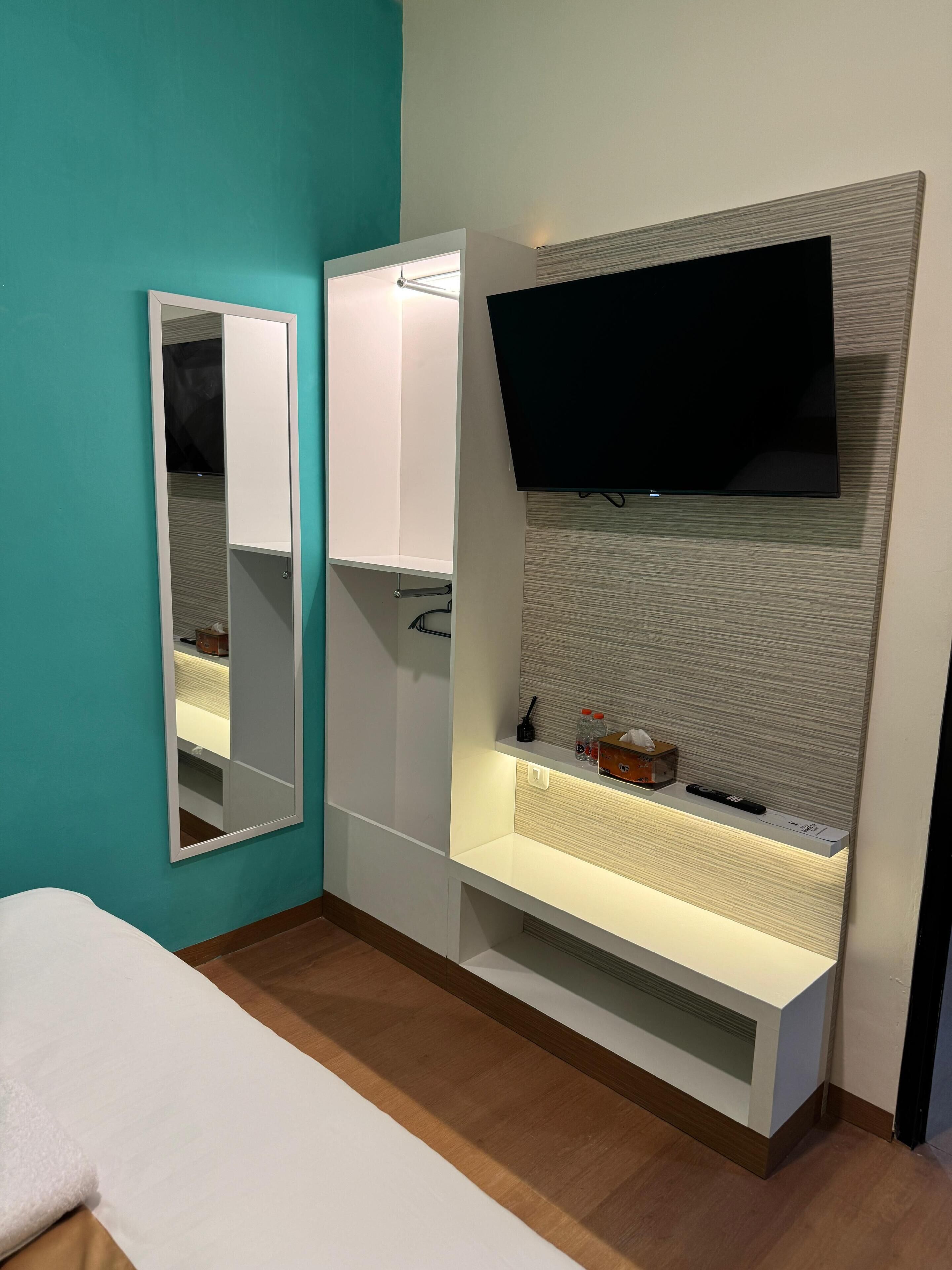 Ein modernes Badezimmer mit Spiegel, Waschtisch und einem angebrachten Fernseher.