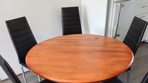 A round wooden table with four black chairs, a metal base, and a light-colored wooden floor. - Nice Two Bedroom Apartment with courtyard/balcony in secure complex (Kelmscott)