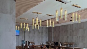 Un ristorante moderno con tavoli e sedie in legno, un'area bar e luci a sospensione.