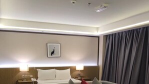 Una camera d'albergo con un letto, una poltrona, un tavolino da caffè e un comodino con il telefono.