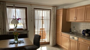 A kitchen with wooden cabinets, a sink, and a dining area with a table and chairs.